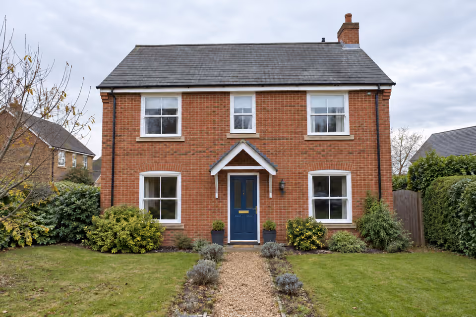 Same illustrative brick house after AI retouching, with brighter exposure and natural colors